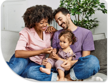 A family is sitting on the ground while holding their child.