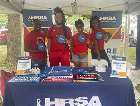 Ryan White HIV/AIDS Program staff stand behind the table at the interactive exhibit booth at the Baltimore AFRAM Festival. 