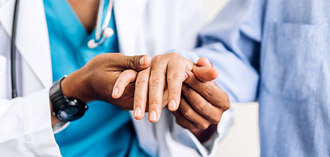 Close-up of a health care professional holding the hand of a patient
