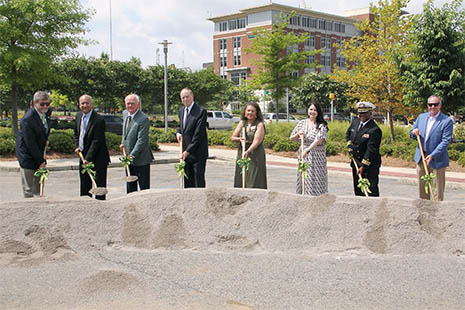 Group portrait of HRSA and UAB attendees holding shovels in front of a large mound of dirt at the groundbreaking ceremony at the University of Alabama.