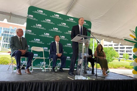 Former U.S. Senator Richard Shelby speaks at a podium while on stage at the groundbreaking ceremony.