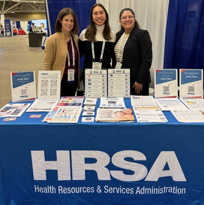 Three HRSA staff members at the HRSA exhibit booth.