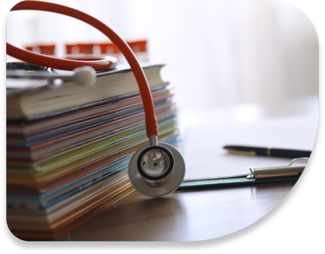 Books sit on top of a desk, while a stethoscope sits on top of the books.