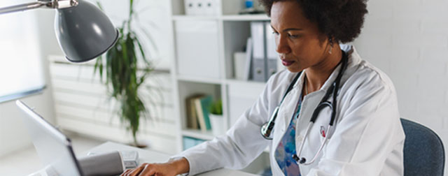 Doctor sitting at a desk using a computer.