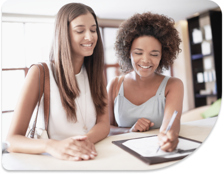 Two girls with one signing a form on a clip board