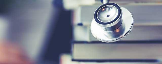 A stethoscope is sitting on top of a stack of books.