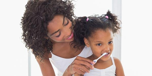 mother with daughter brushing teeth